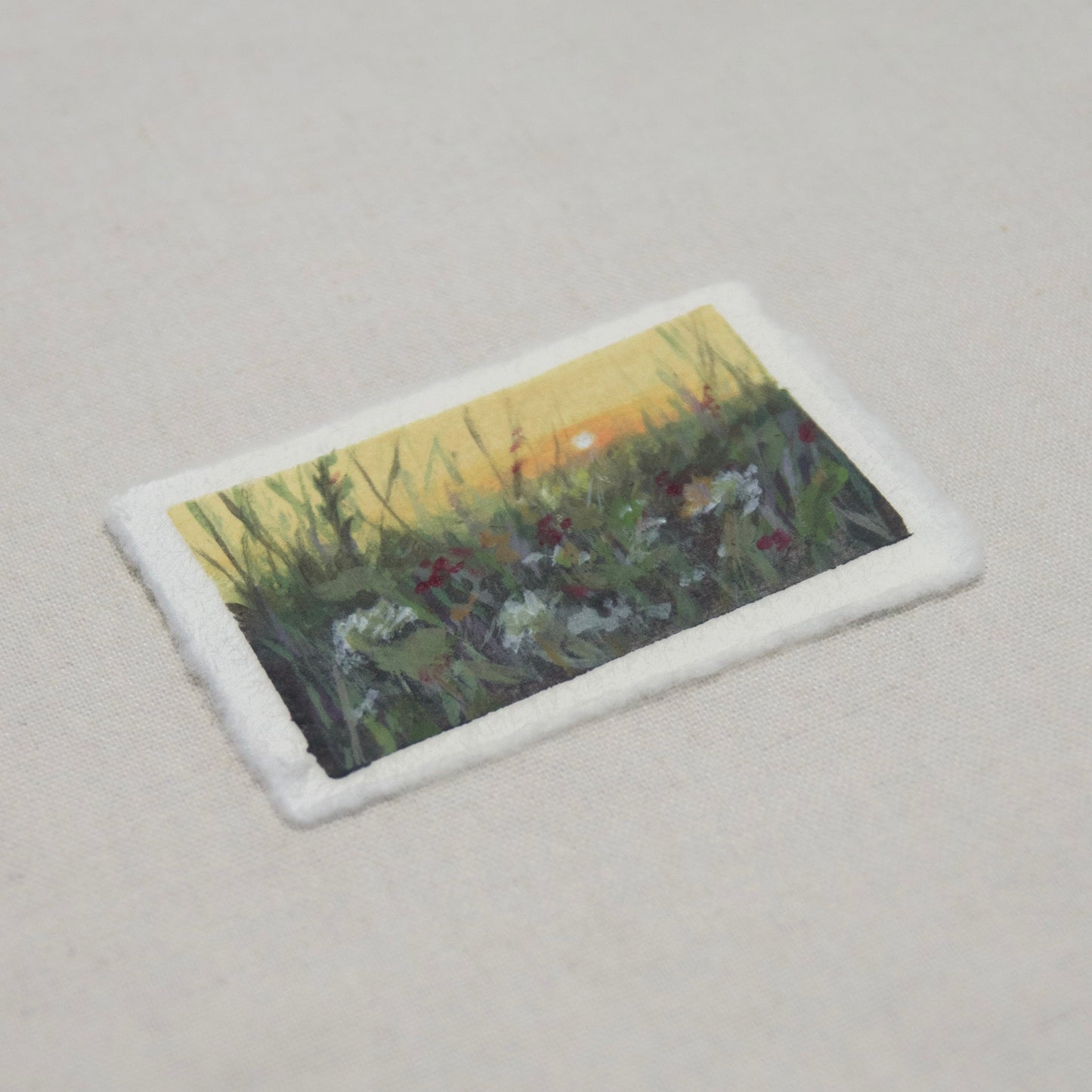 side profile of a floral field at golden hour on deckled edge cotton paper