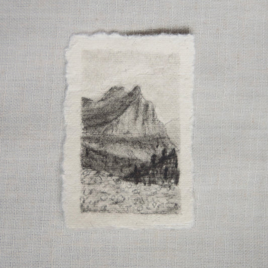 A charcoal sketch of a view from 'going to the sun road' in Glacier National Park on deckled edge paper, with visible strokes and shading created by artist Laura Van Moorleghem