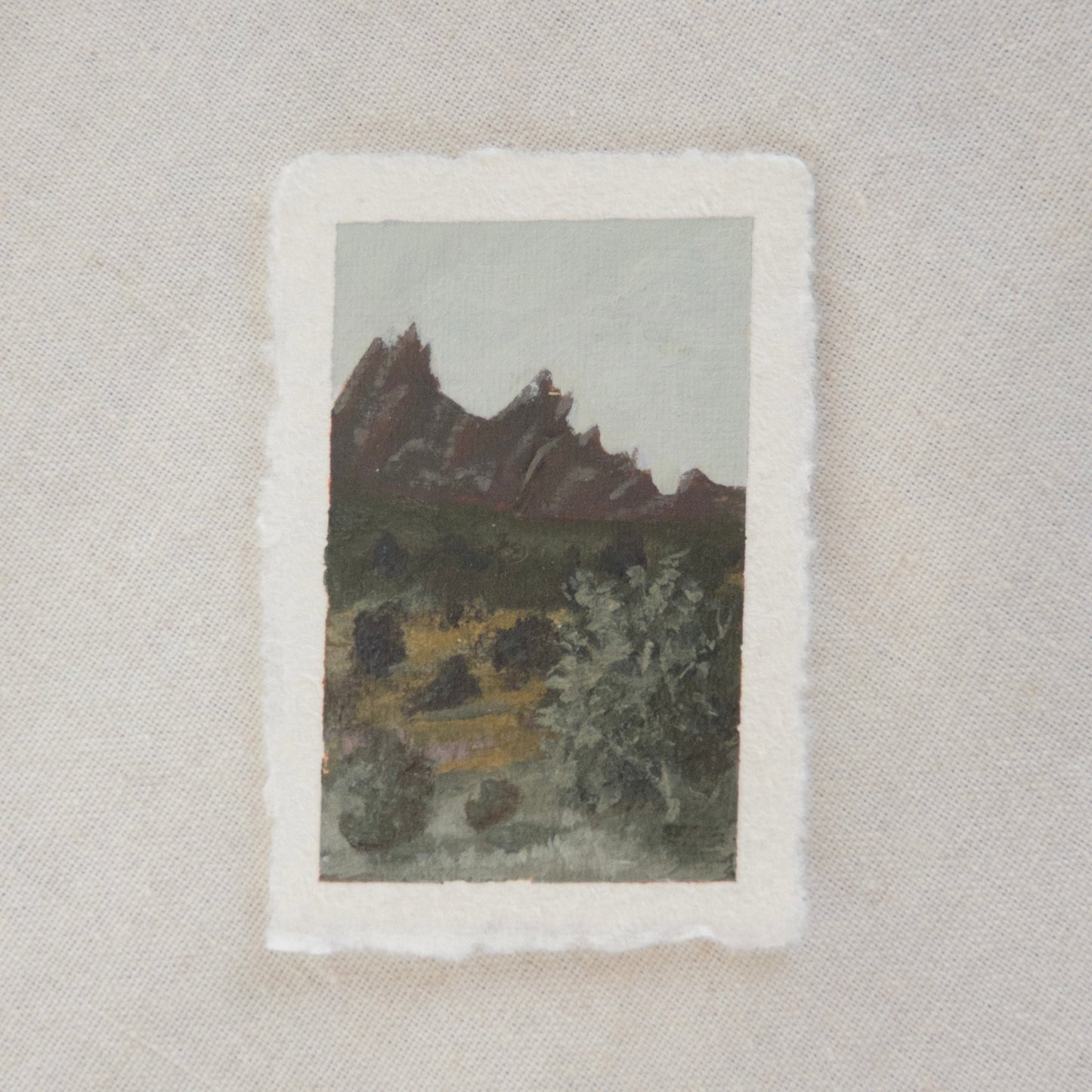 A miniature painting depicting pinnacles and trees, executed in a soft, impressionistic style on deckled edge paper in acrylic. created in Pinnacles National park by artist Laura Van Moorleghem
