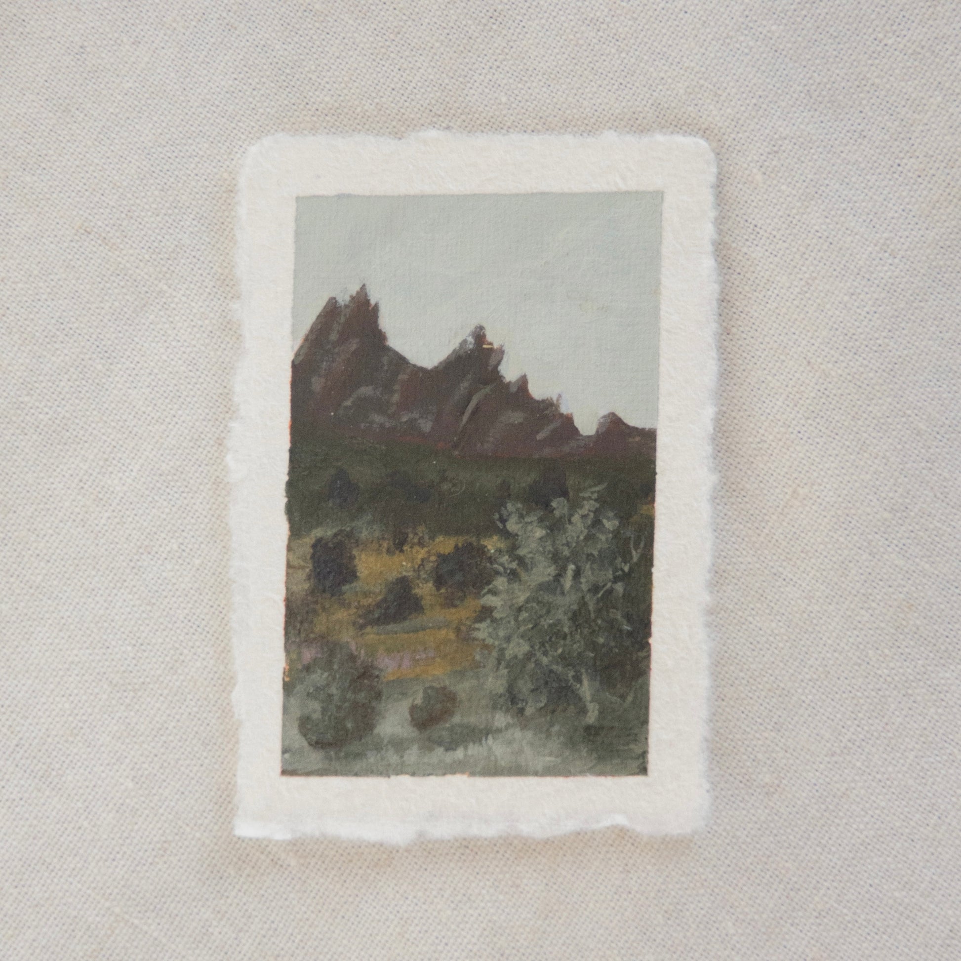 A miniature painting depicting pinnacles and trees, executed in a soft, impressionistic style on deckled edge paper in acrylic. created in Pinnacles National park by artist Laura Van Moorleghem