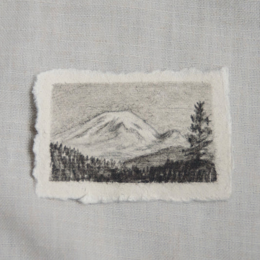 A sketch of Mt. Rainier in a landscape setting, executed in charcoal and pencil on deckled edge paper by Laura Van Moorleghem for 'for the land' collection