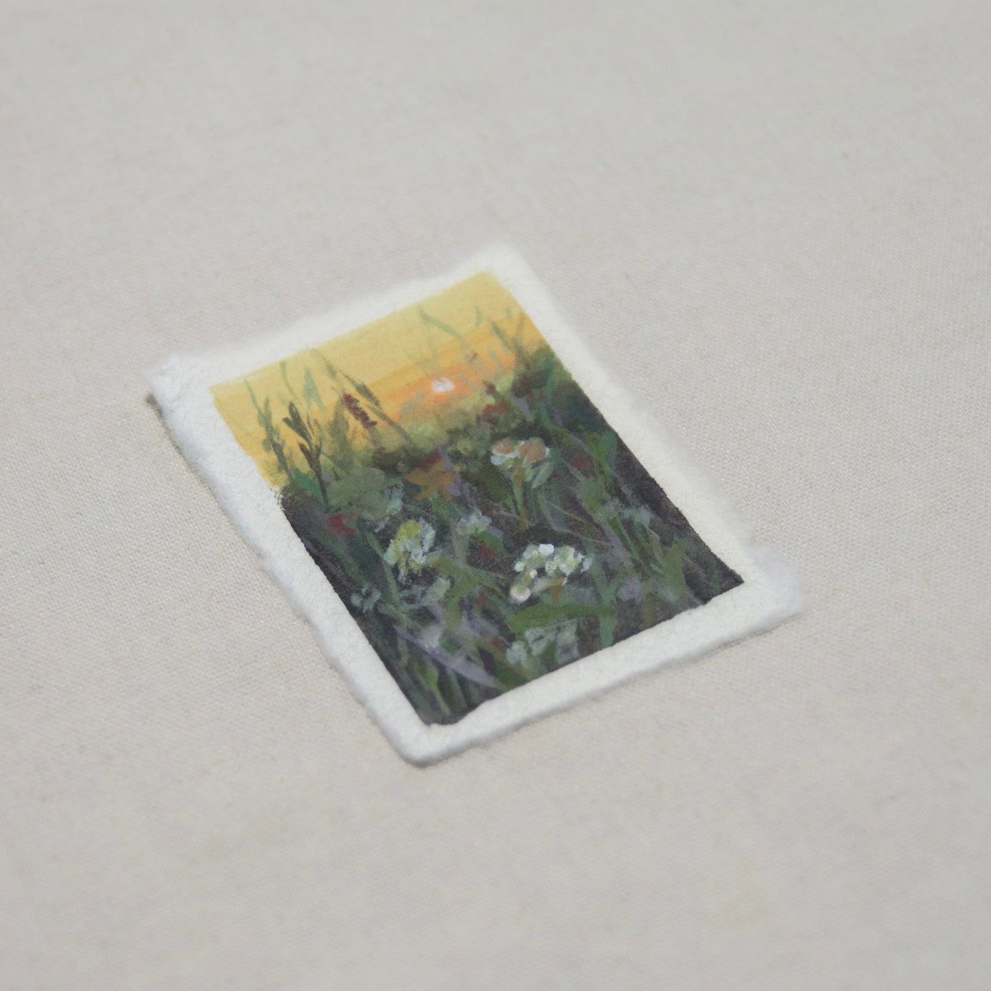 side profile of a mini painting in acrylic and gouache depicting a sunset in a flower field