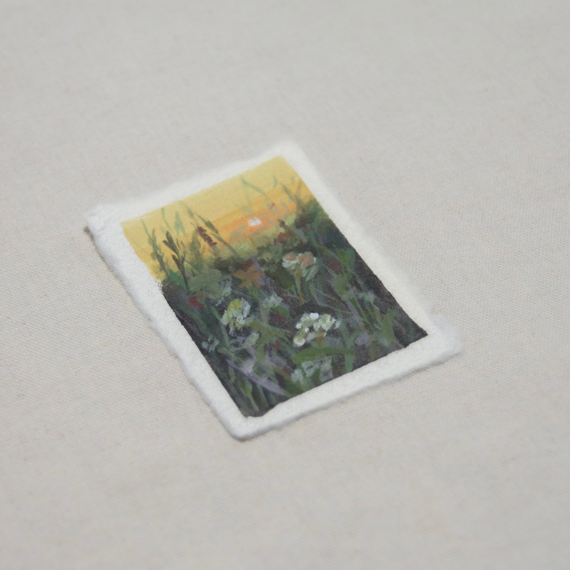 side profile of a mini painting in acrylic and gouache depicting a sunset in a flower field