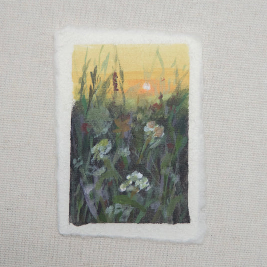 A small artwork titled 'In Bloom', featuring a floral scene with gouache and acrylic paints on cotton rag paper with a deckled edge by artist Laura Van Moorleghem