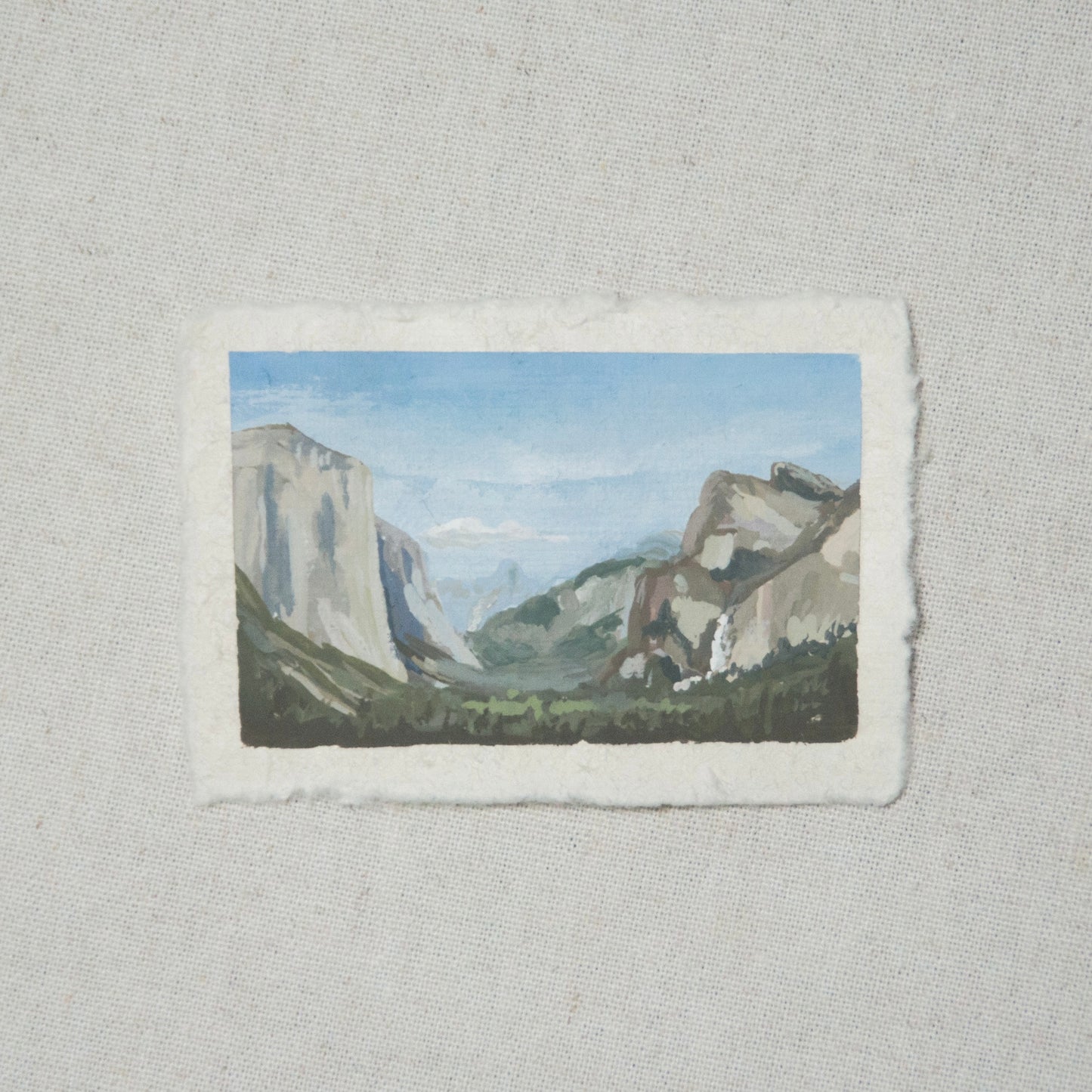 A miniature painting depicting a landscape view of Yosemite National Park Tunnel View, featuring mountains and sky, executed in gouache on deckled edge paper.