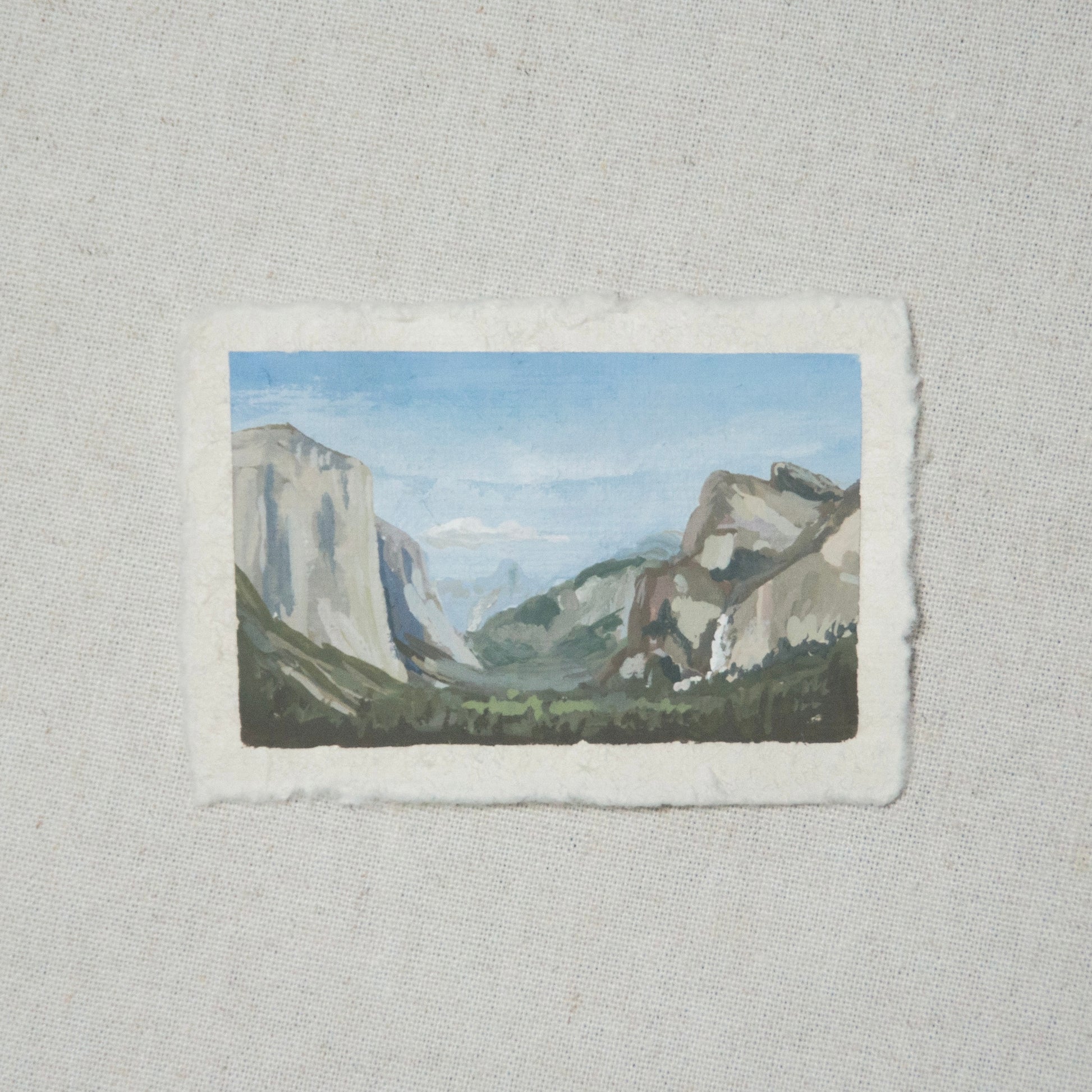 A miniature painting depicting a landscape view of Yosemite National Park Tunnel View, featuring mountains and sky, executed in gouache on deckled edge paper.