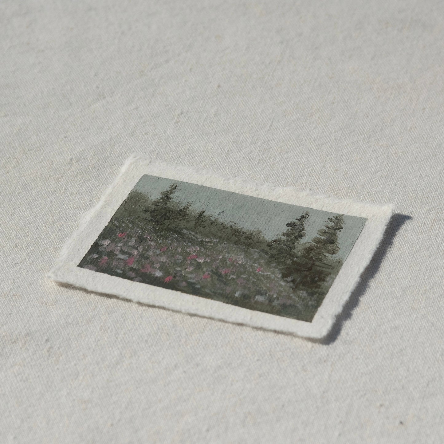 Side profile of hillside filled with colorful wildflowers and pine trees painting on deckled edge 100% cotton rag paper 